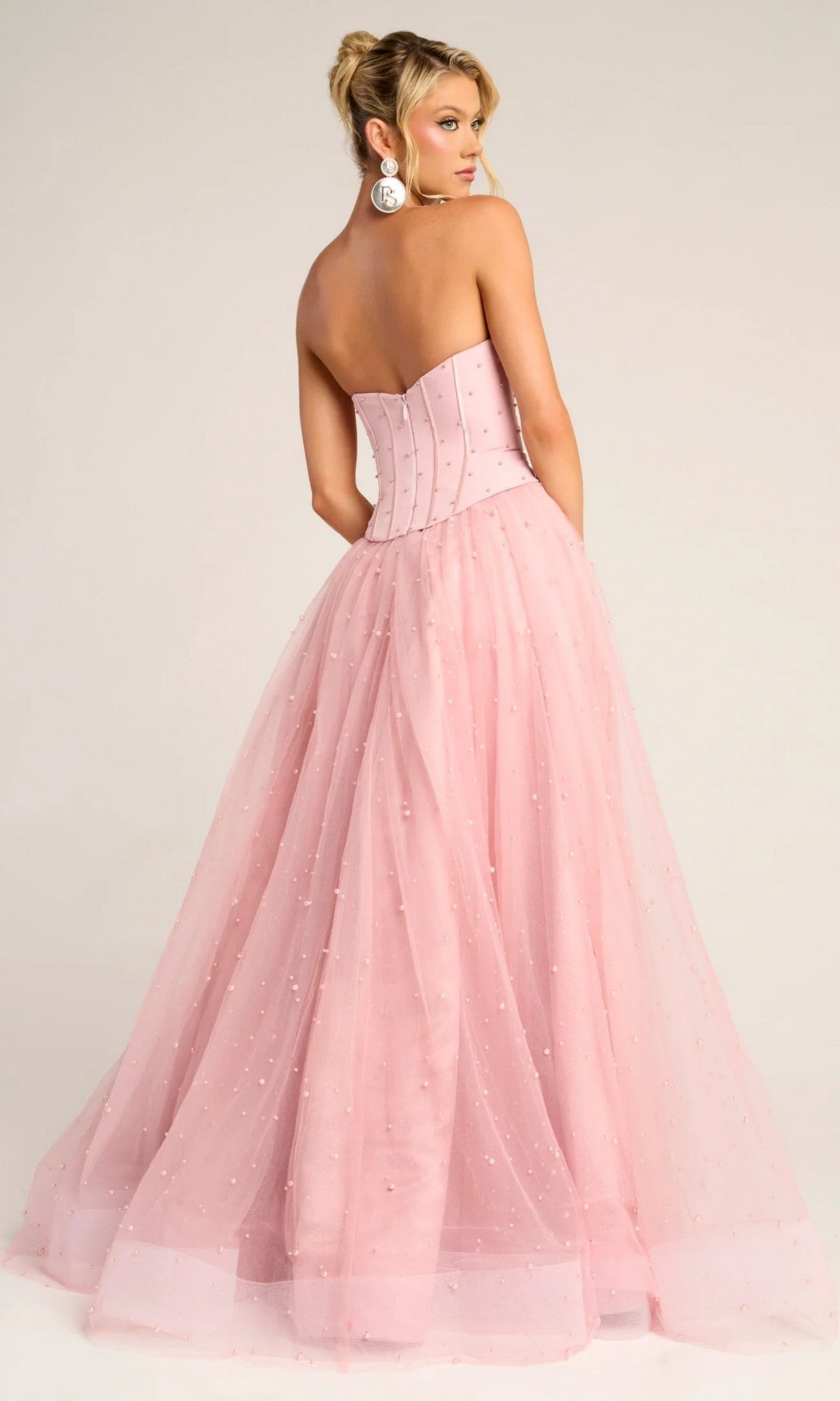 Model wears the Portia and Scarlett PS26034 long formal dress, featuring a strapless corset bodice and full glitter tulle skirt, standing with her back to the camera against a plain background.